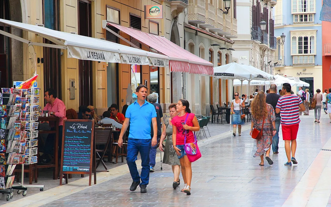 A pedestrian street in the historic centre of Málaga lined with cafés, awnings and shoppers, minutes from the Museo Picasso Málaga